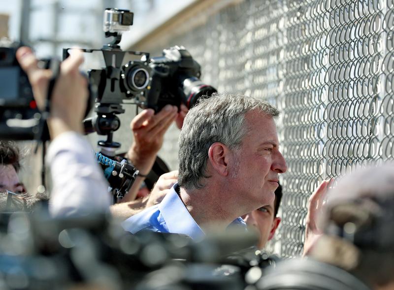 Mayor Bill de Blasio looks through a closed gate at the Port of Entry facility, in Fabens, Texas.