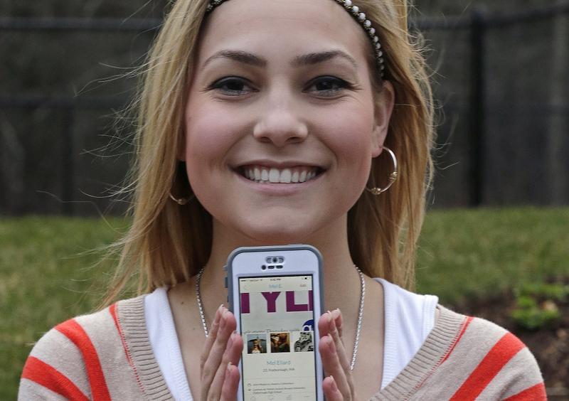 In this April 23, 2014 photo, Melissa Ellard poses showing her Hinge profile on her iPhone, in Foxborough, Mass. Ellard says she wouldn’t have gone on a date in the past six months if not for Hinge.