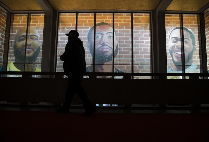 A man is silhouetted as he walks by enlargements of self-portraits made by a formerly incarcerated artists in Philadelphia