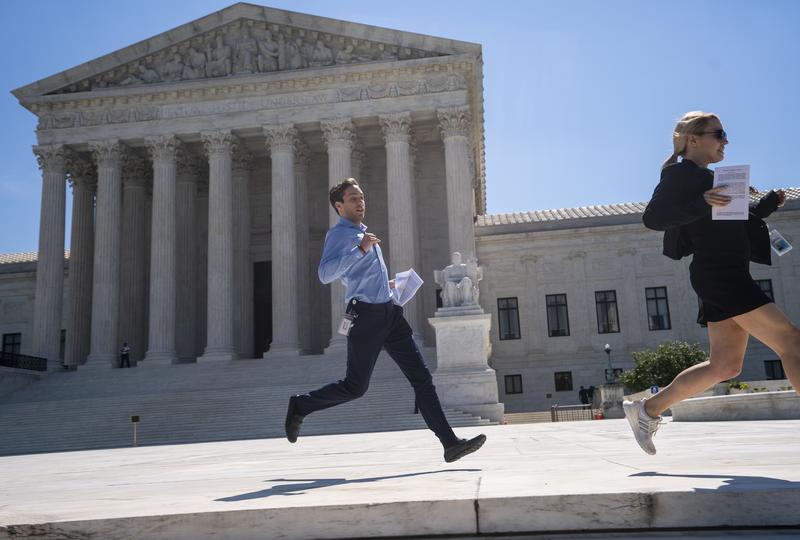 News agency interns sprint across the plaza at the Supreme Court with copies of the justices' final decisions of the term, in Washington, Thursday, June 27, 2019.