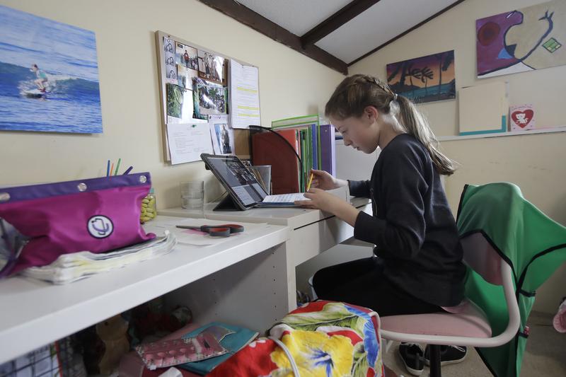 In this Thursday, March 19, 2020, photo, Rachel Keenan, 9, takes a live class online at her home in San Francisco.