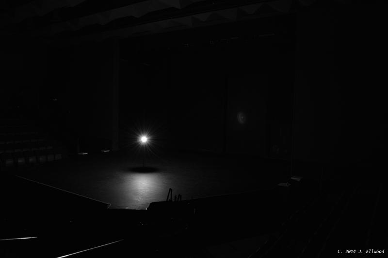 A Ghost Light on an empty stage in a darkened theater, following the tradition of leaving a lamp lit on an empty stage. Taken at the WildWood Arts Center, Little Rock, Arkansas.
