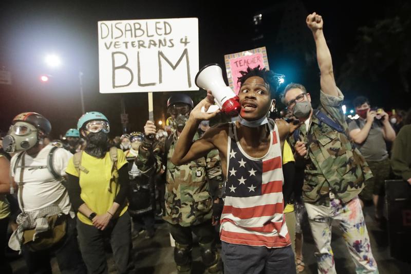 A demonstrator shouts slogans using a bullhorn next to a group of military veterans during a Black Lives Matter protest at the Mark O. Hatfield United States Courthouse July 26, 2020, in Portland, OR.