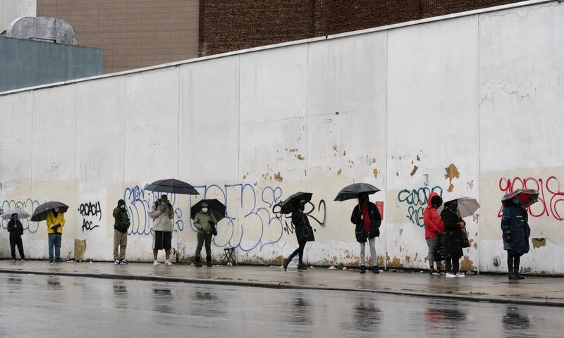 People under umbrellas practice social distancing as they line up for early voting, Friday, Oct. 30, 2020, in Brooklyn.