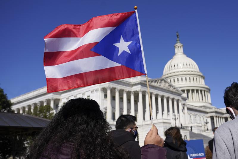 A woman waves the flag of Puerto Rico during a news conference on Puerto Rican statehood on Capitol Hill in Washington, Tuesday, March 2, 2021.