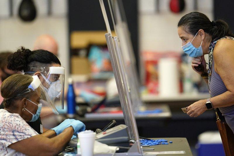 In this July 14, 2020 file photo, a voter, right, shows her identification to a Harris County election clerk before voting, in Houston. 