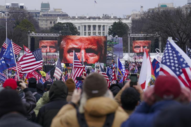 The face of President Donald Trump appears on large screens as supporters participate in a rally in Washington, Jan. 6, 2021.