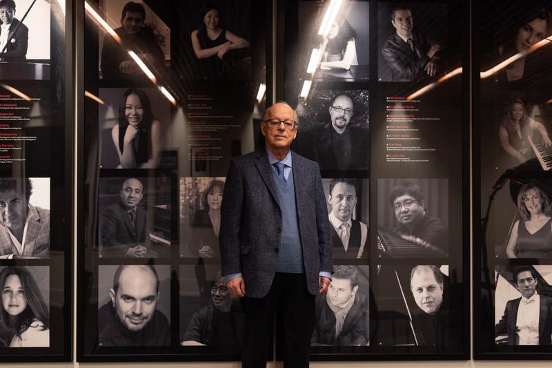 Solomon Mikowsky in the Solomon Mikowsky Recital Hall, with portraits of former students