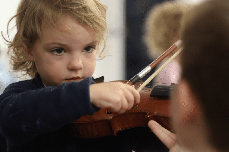 Trying out a violin at the instrument petting zoo.