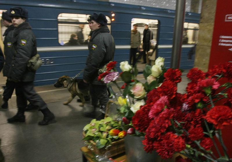 Russian police patrol near flowers left in memory of the victims of a blast at the Park Kultury metro station in Moscow on March 29, 2010. 