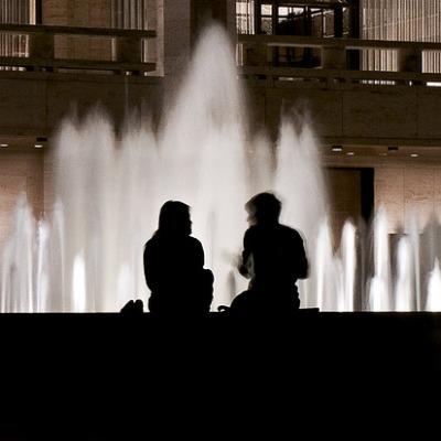 A couple sits beside the Lincoln Center<br/> fountain