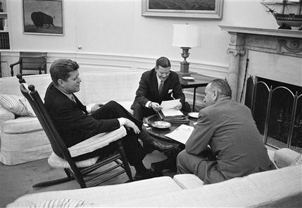 In March 16, 1961, JFK sits in his favorite rocking chair in his office during a meeting with Secretary of Defense Robert McNamara and Vice President Lyndon B. Johnson, right, at the White House.